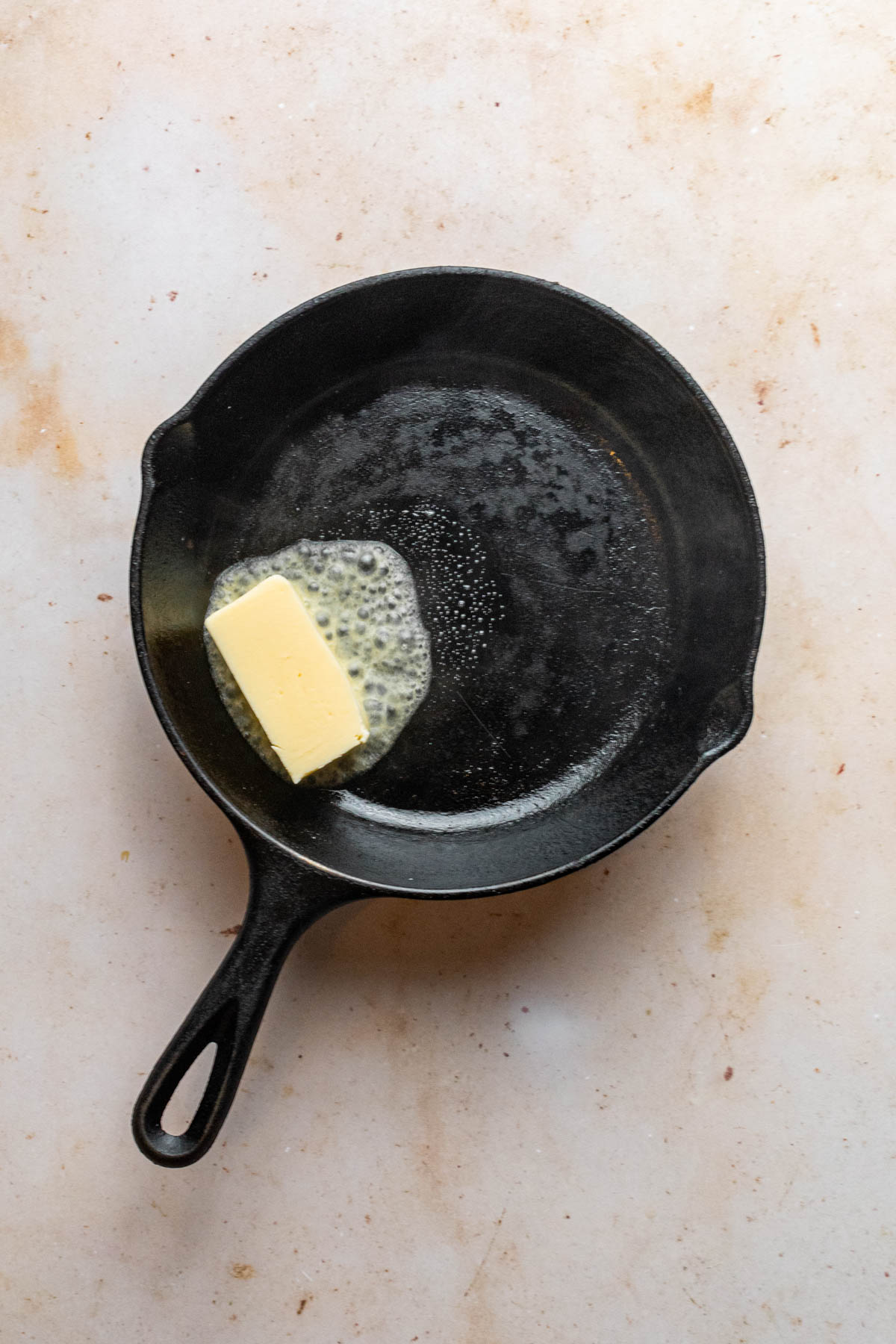 Butter melting and sizzling in a cast iron skillet.