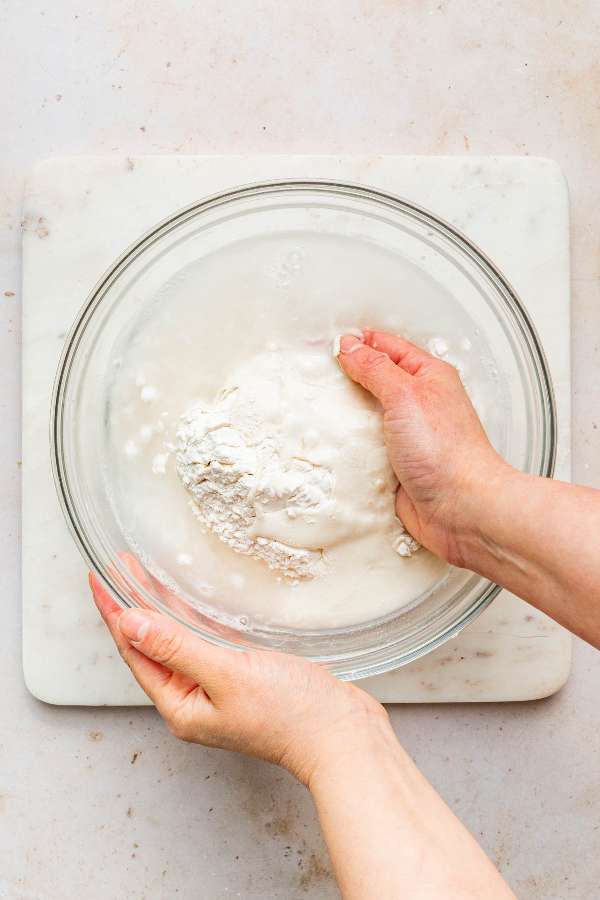 A hand reaching into a bowl of unmixed ingredients.