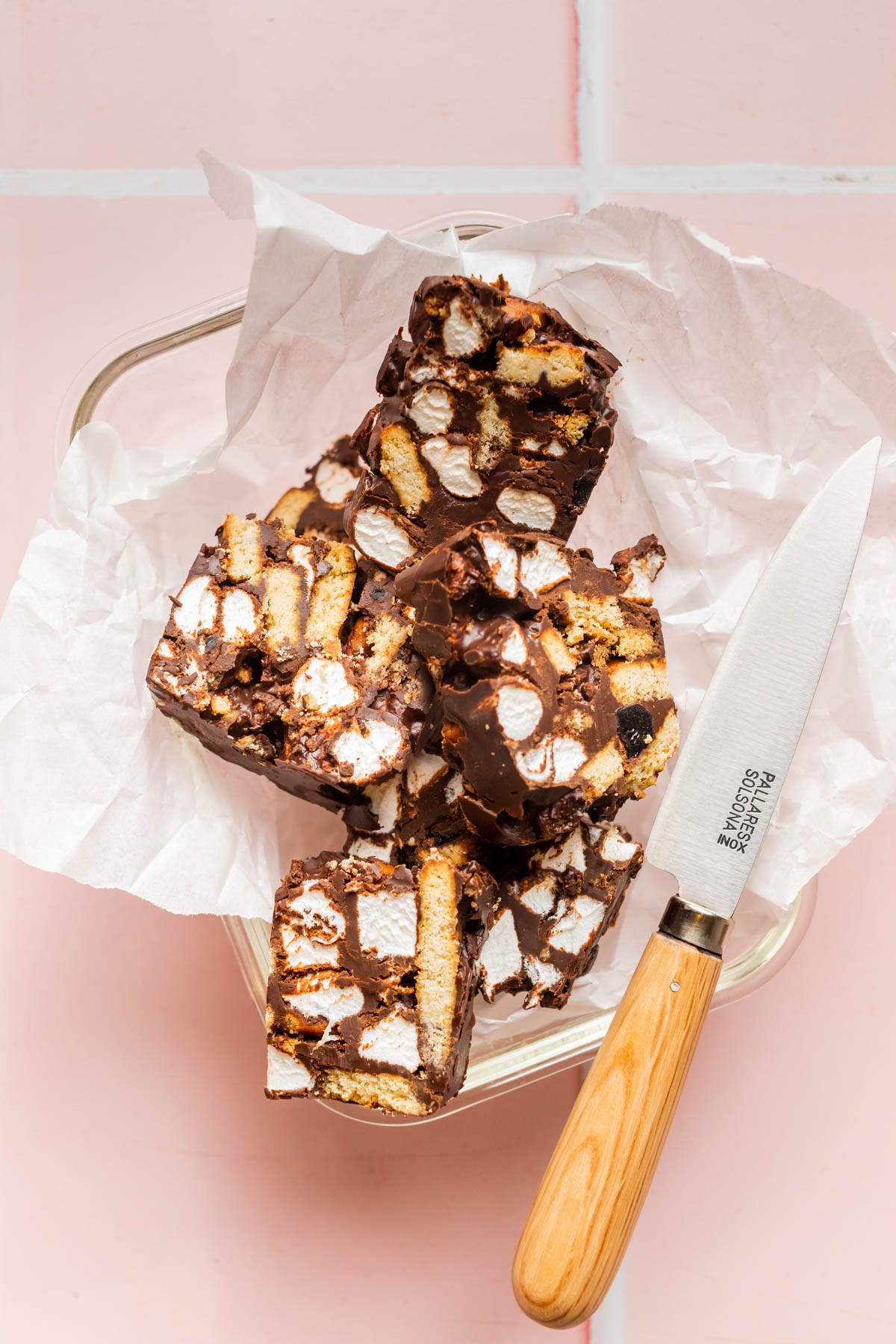 Rocky road pieces in a container with paper and a knife.