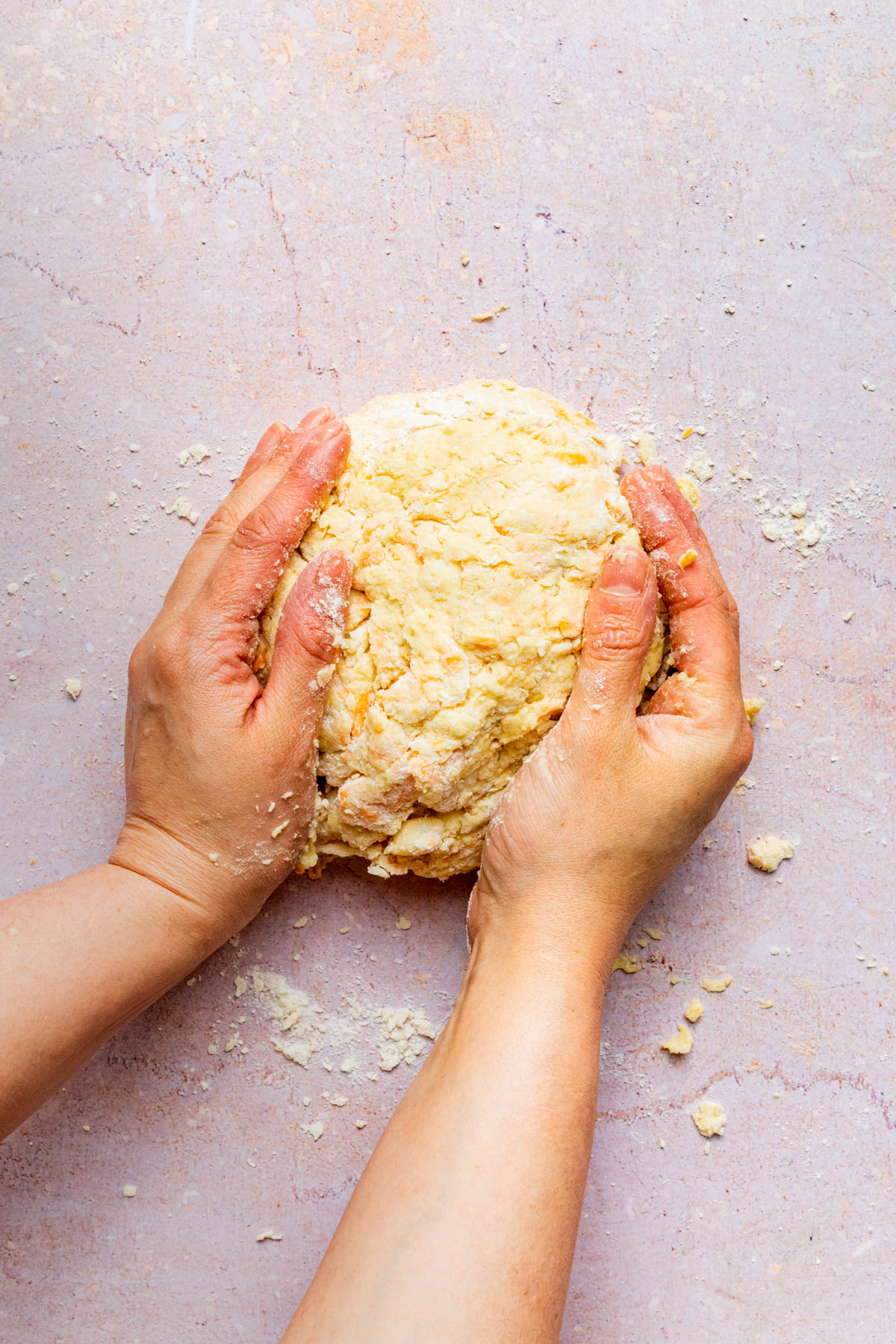 Dough being brought together with hands.